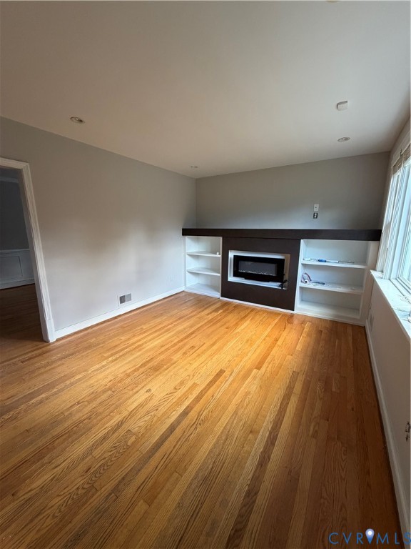 Room featuring wood-finish flooring, recessed lighting, and a built-in fireplace mantle with integrated white shelving