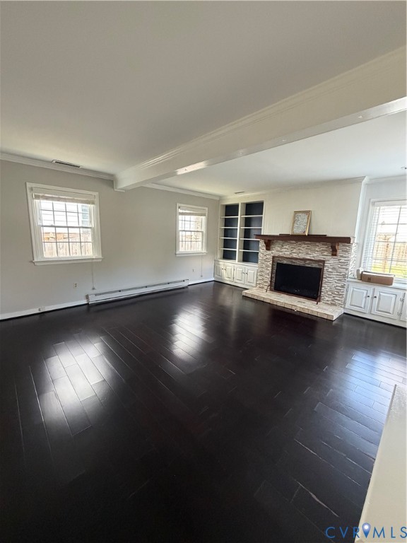 Living area featuring wood-finish flooring, a fireplace with a stone-finish surround and wood mantel, and floor-to-ceiling built-in cabinetry