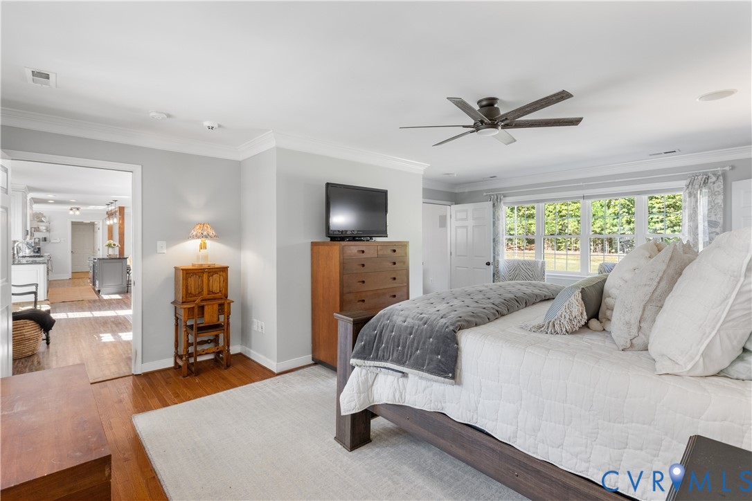 1st Floor Bedroom featuring wood-finish flooring, crown molding, ceiling fan, Adjoining luxury bath