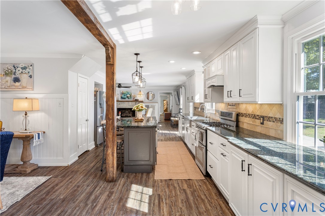 Kitchen featuring shaker-style cabinetry, stone countertops, central island, exposed timber support beam, pantry