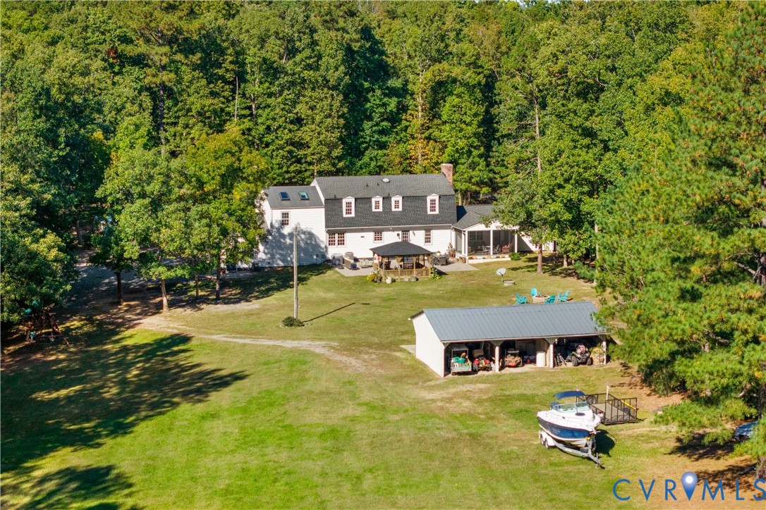 Two-story residence featuring a multi-dormer roofline, skylights, an attached screened porch, a detached multi-bay open-air structure, and7. 9 acreage