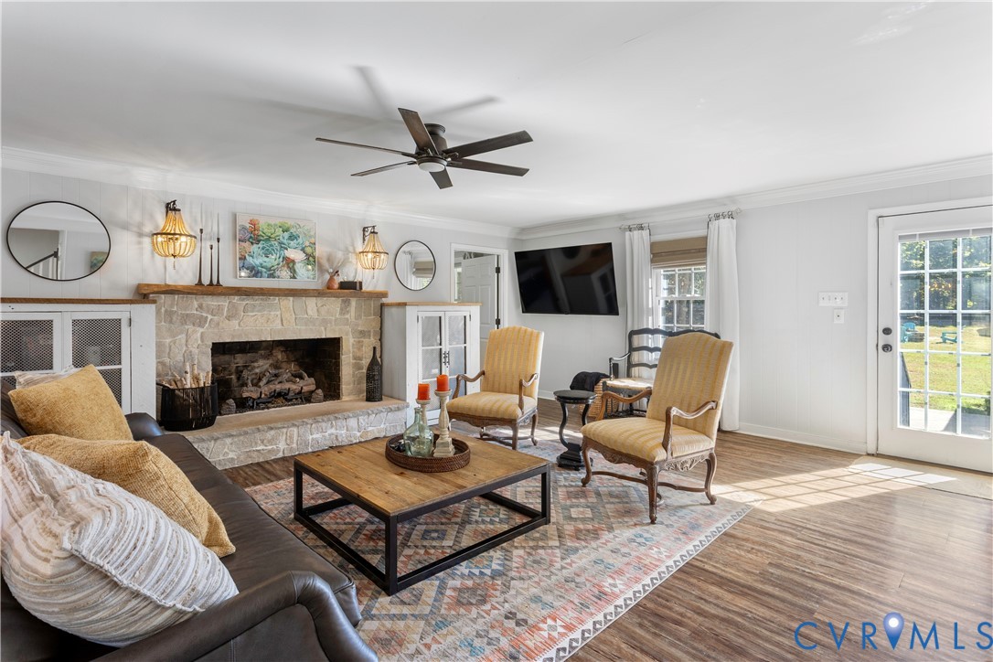 Stone-surround fireplace with a wood mantel, ceiling fan, and full-glass panel rear entry door. Easy access to the rear courtyard.