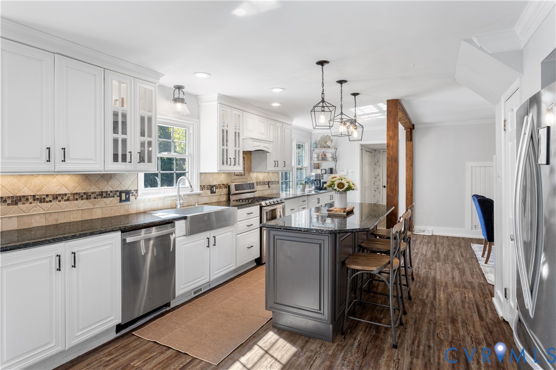 Kitchen featuring white, Granite stone countertops, an apron-front stainless steel sink, central island,