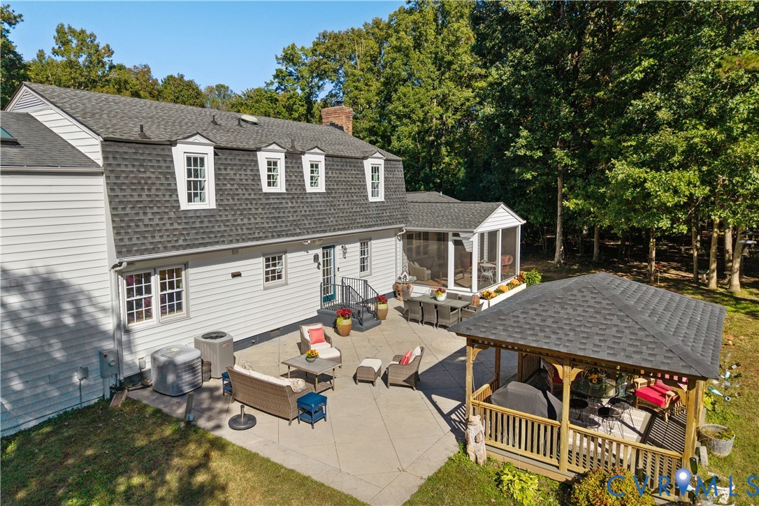 Rear exterior featuring a gambrel roof, light-toned horizontal siding,concrete patio, covered gazebo, and an screened porch