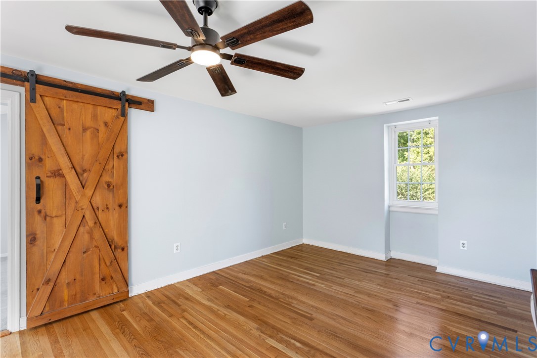 Wood-finish flooring, wood-toned sliding barn door with black iron hardware,