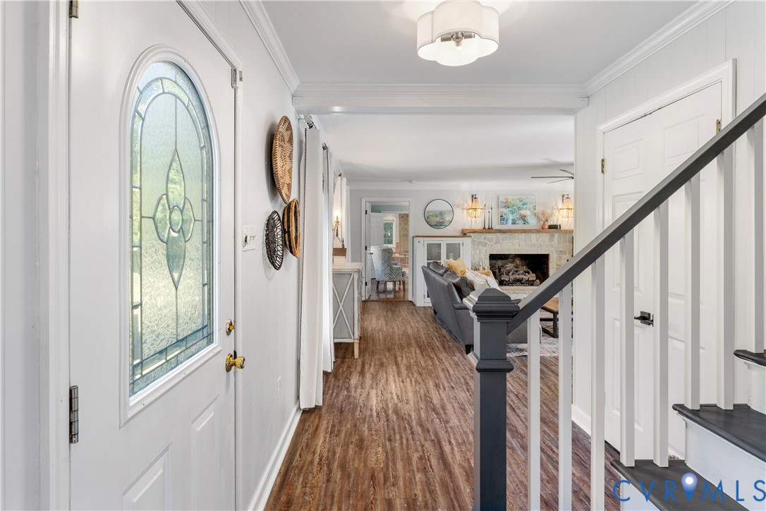 Entryway featuring an arched glass-panel insulated front door crown molding, coat closet