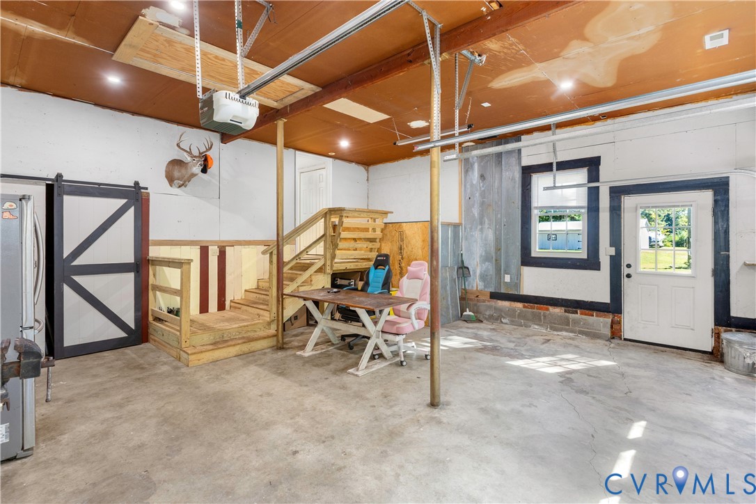 Multi-purpose space featuring concrete flooring, a wooden staircase, sliding barn-style door, and recessed lighting