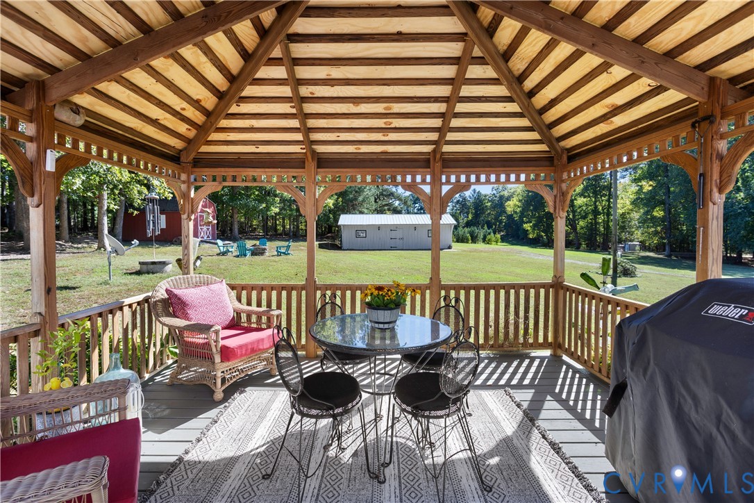 Covered wooden gazebo featuring a vaulted shiplap ceiling, open-post architecture, and integrated perimeter railing