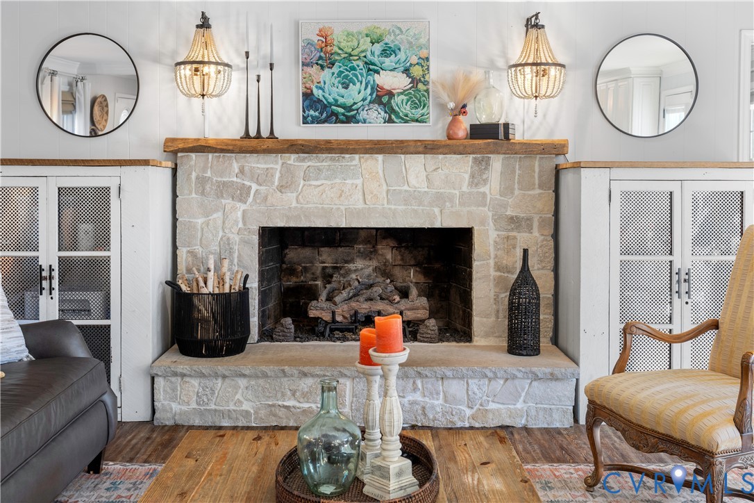 Fireplace featuring a light-toned stone surround, a natural wood mantel, a raised stone hearth,