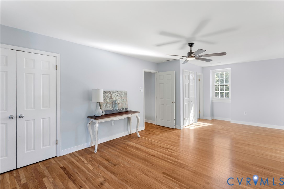 2nd floor primary Room featuring wood-newly finished flooring, a multi-panel ceiling fan with integrated lighting, dual-panel closet doors, and a multi-pane window