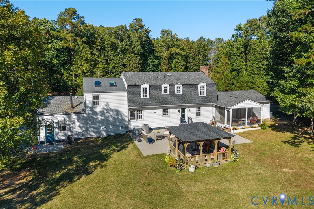 Multi-level residence featuring a shingled roof with skylights, a concrete patio, a detached wooden gazebo, and a screened-in porch, all situated on a 7.9 acres