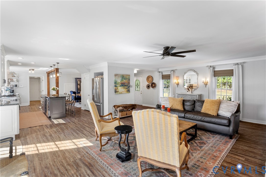 Open-concept interior featuring LVT flooring, a central island with built-in cabinetry, recessed lighting, and a ceiling fan