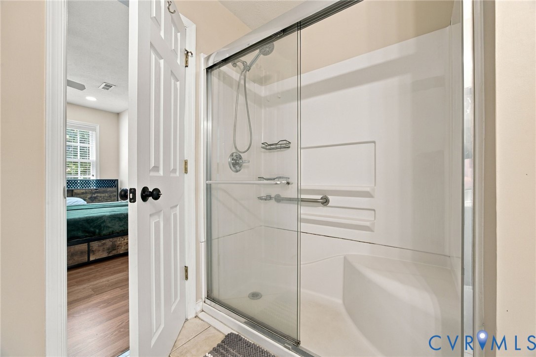 Bthroom Walk-in shower featuring a glass sliding enclosure, built-in bench seat, integrated shelving, and adjustable handheld shower head