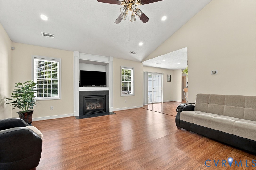 Living Room with Vaulted ceilings, wood-finish flooring, built-in fireplace with recessed media niche, and recessed lighting