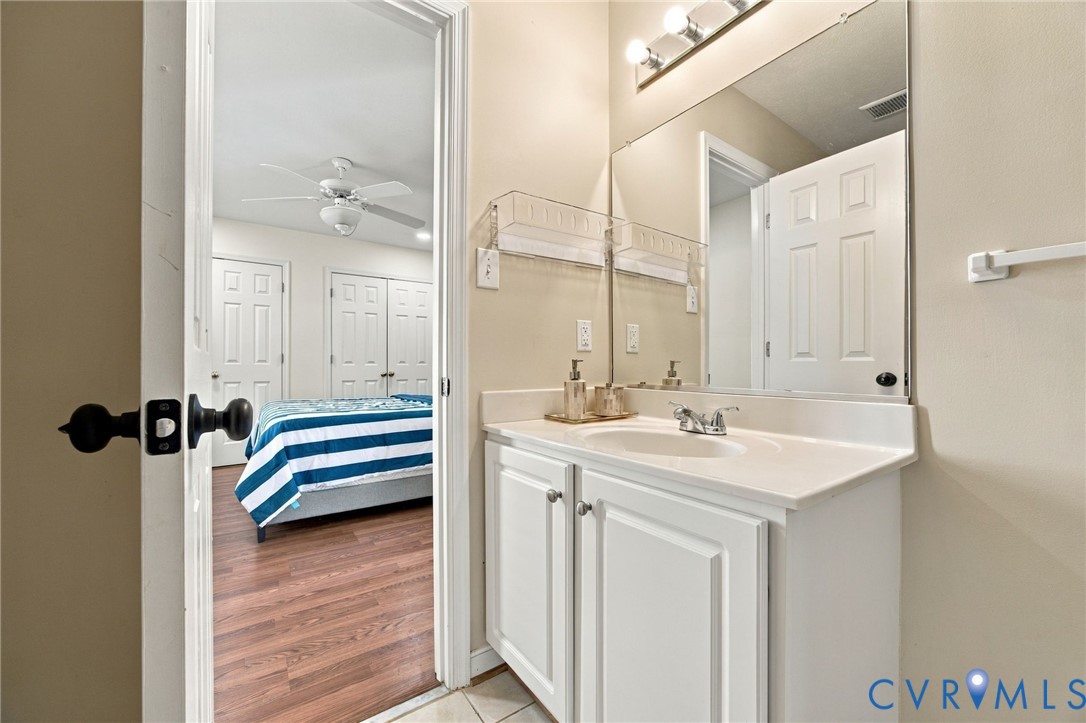 Bathroom Vanity featuring a white cabinetry base, integrated countertop and sink, chrome dual-handle faucet, full-width wall mirror, and overhead tri-light fixture