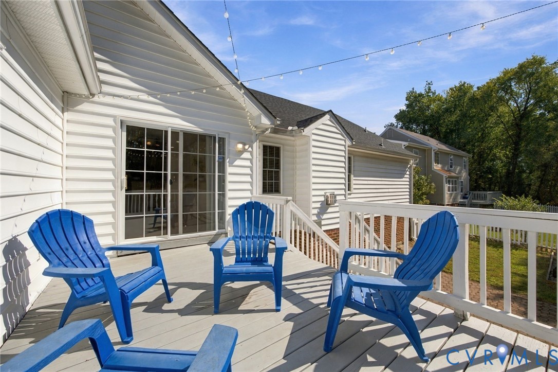 Elevated deck featuring white composite railing, horizontal siding, and glass sliding doors