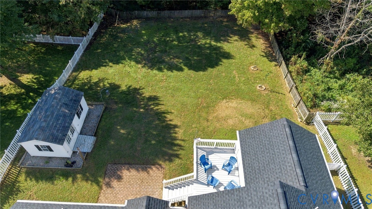 Expansive fenced backyard featuring a large lawn, a detached storage structure, an elevated composite deck, and a paver patio