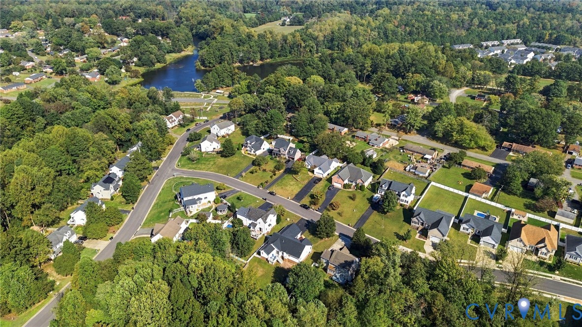 Aerial view featuring established residential lots, mature tree canopy, and proximity to a local water feature