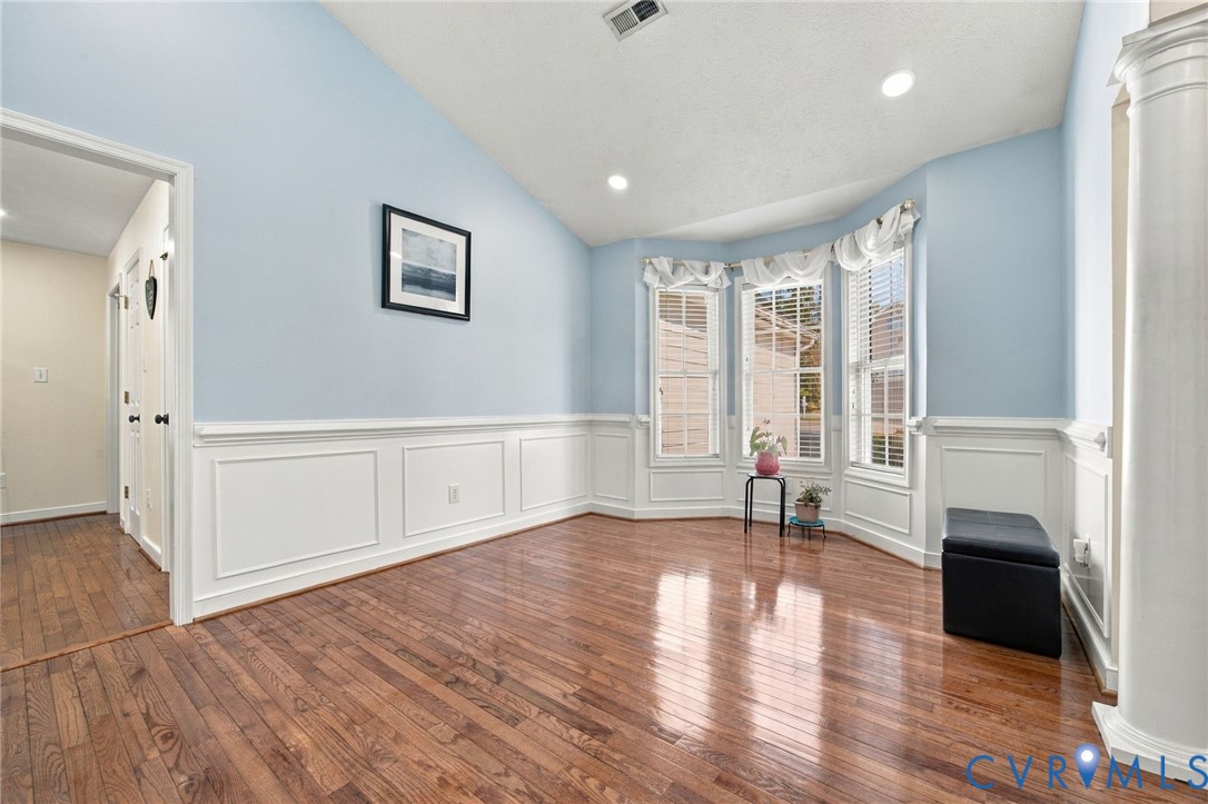 Dining Area, High ceilings featuring an arched opening with columns, hardwood flooring, and wainscoting detailing Dining Area, High ceilings featuring an arched opening with columns, hardwood flooring, and wainscoting detailing