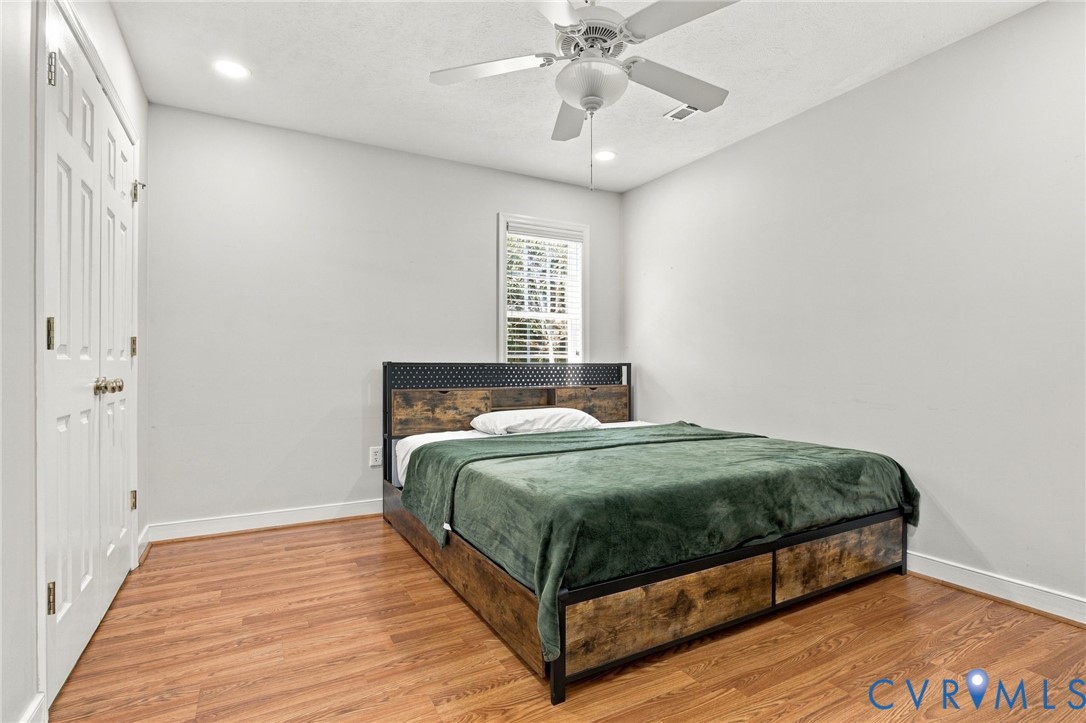 Bedroom with Wood-finish flooring, recessed lighting, ceiling fan, and double-panel doors