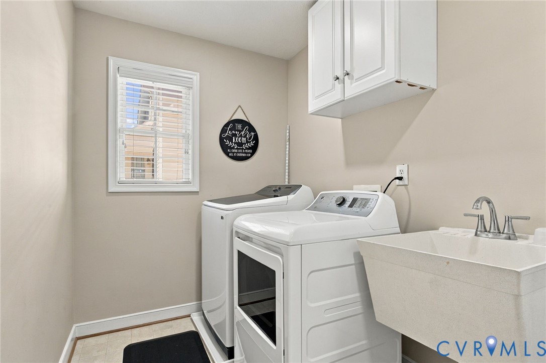 Utility room featuring wall-mounted white cabinetry, a single-basin utility sink with a chrome faucet, and a window with blinds