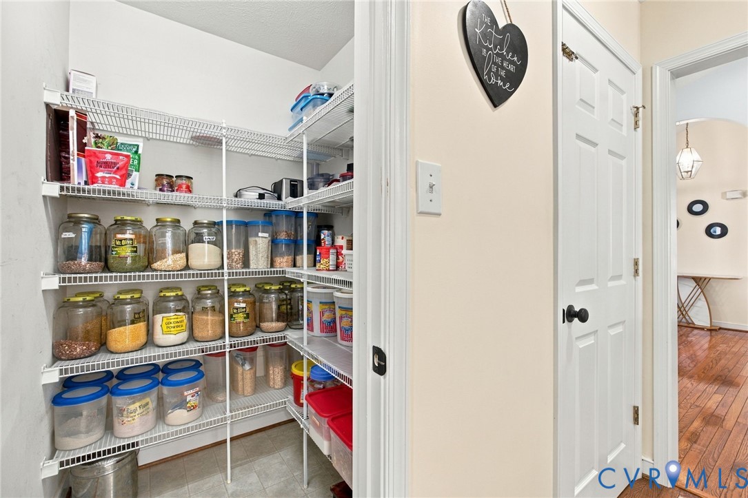 Walk-in pantry featuring white wire shelving and neutral tile flooring, enclosed by a six-panel door