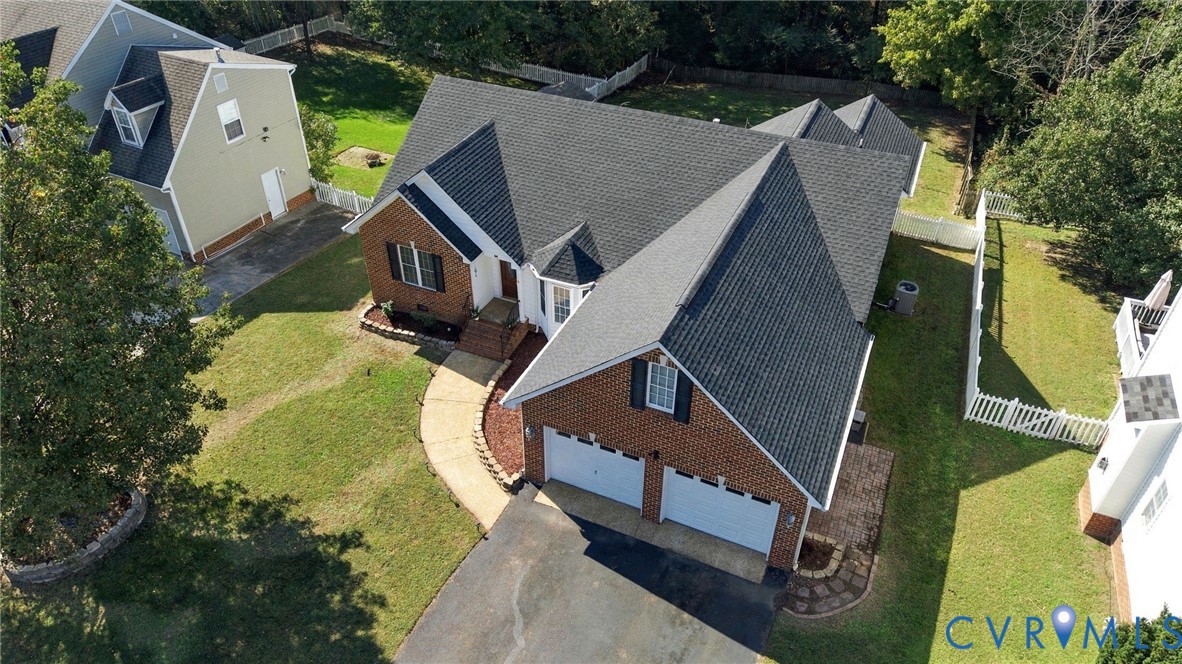 Brick exterior featuring an asphalt shingle roof, a two-car garage, and a curved concrete walkway