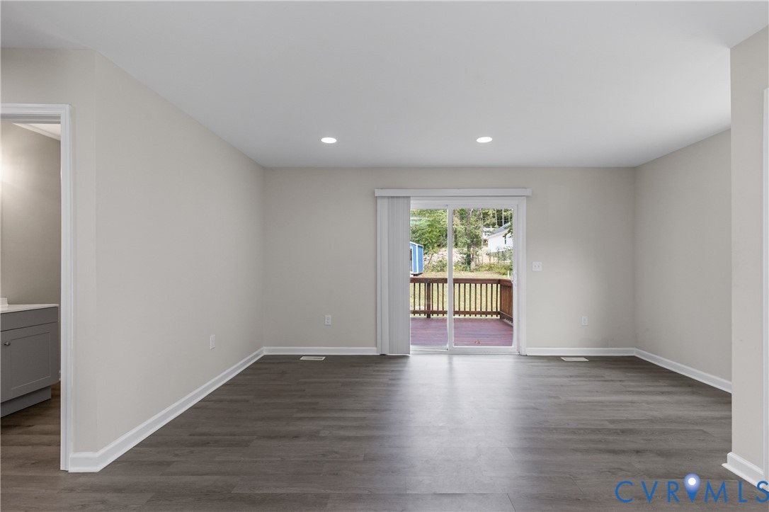 Neutral interior featuring wood-finish flooring, recessed lighting, and a glass sliding door providing outdoor deck access