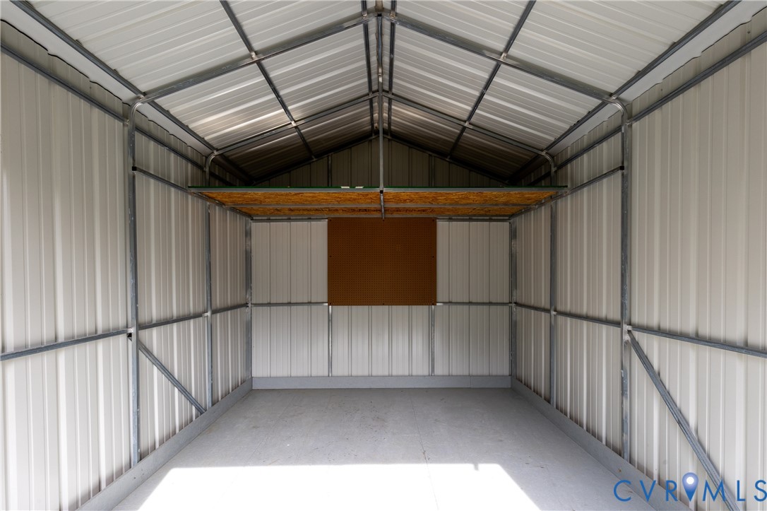 Outbuilding featuring a corrugated metal exterior, vaulted ceiling, metal structural framing, and an elevated storage platform