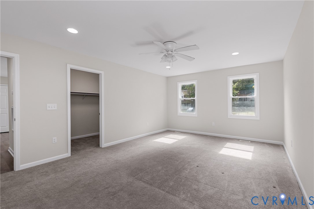 Neutral-toned room featuring plush wall-to-wall carpeting, recessed lighting, a white ceiling fan with integrated light fixture, and two windows