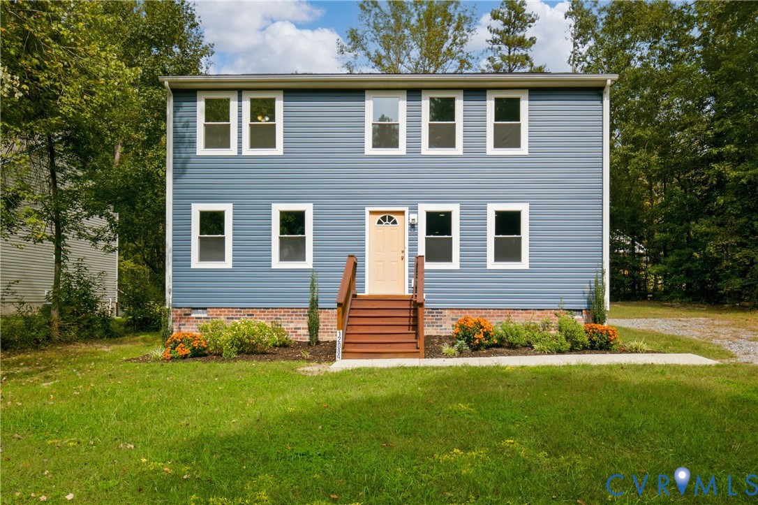 Two-story home featuring blue horizontal siding, a red brick foundation, a centered wooden staircase with handrails, and a multi-pane glass entry door