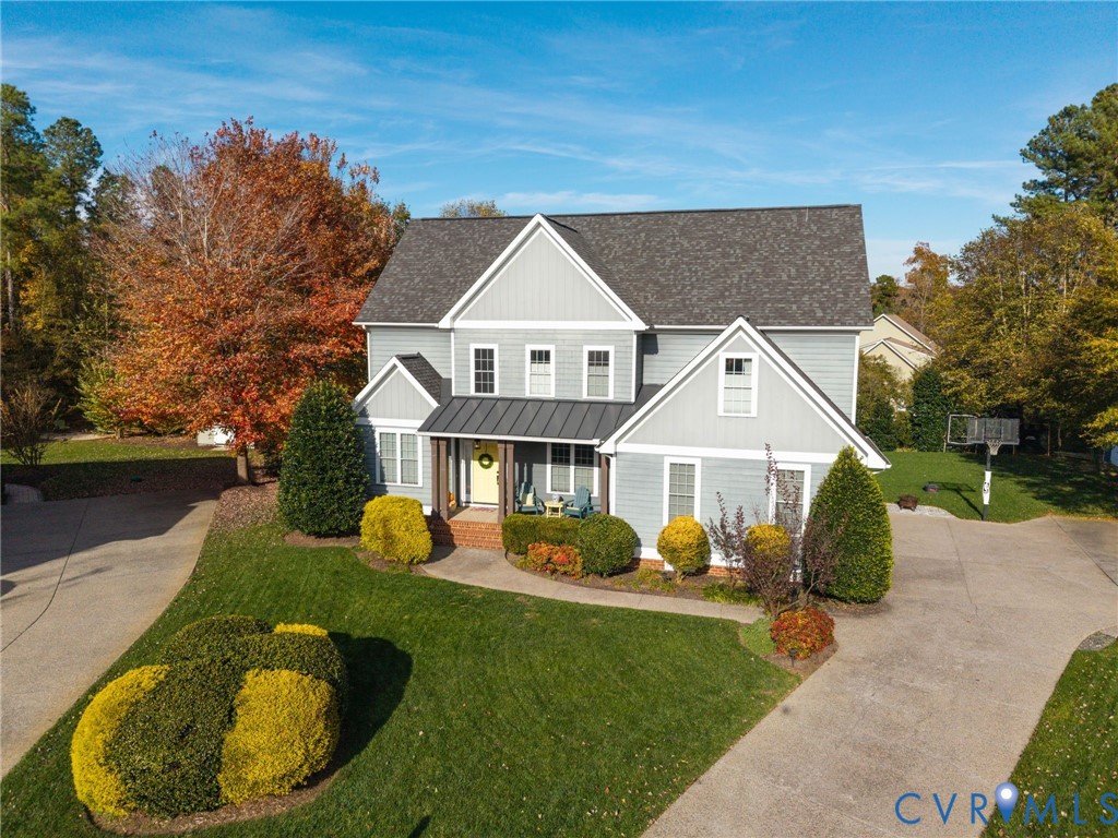 Two-story exterior featuring light gray horizontal siding, a gabled roofline with asphalt shingles, metal roof accents, and a concrete driveway
