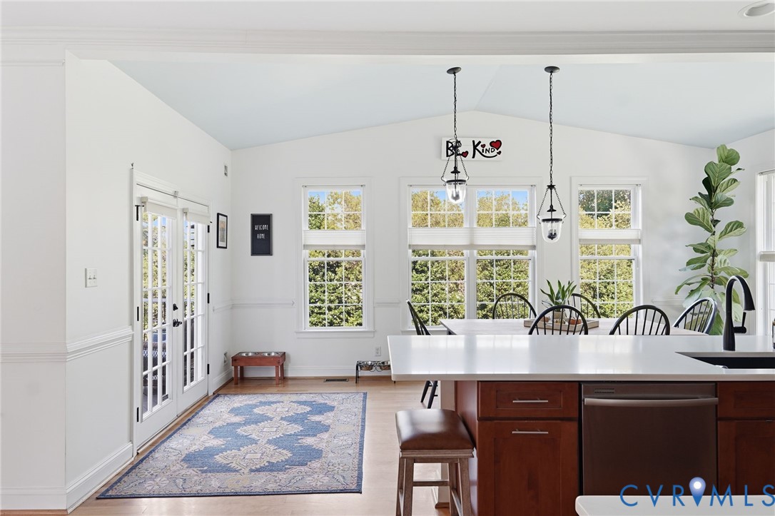 Kitchen featuring a central island with a quartz countertop, wood-finish cabinetry, metal pendant lighting, double French doors, and multi-pane windows