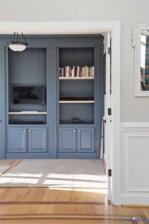 Custom built-in cabinetry featuring fluted detailing, lower storage cupboards, open shelving, integrated beadboard paneling, and an attached semi-flush mount light fixture Custom built-in cabinetry featuring fluted detailing, lower storage cupboards, open shelving, integrated beadboard paneling, and an attached semi-flush mount light fixture