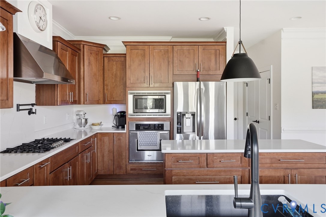 Kitchen featuring rich-toned cabinetry, quartz countertops, stainless steel appliances, a built-in wall oven and microwave, and a matte black gooseneck faucet