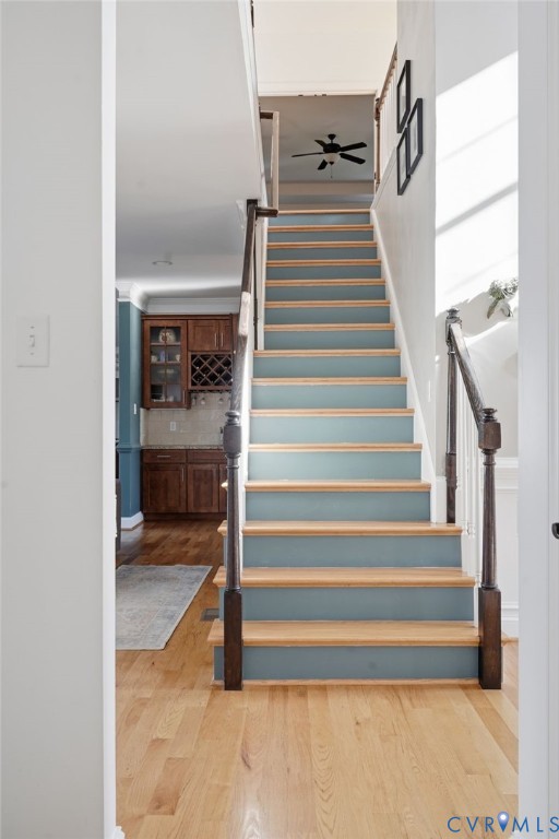 Staircase featuring wood-finish treads, painted risers, and dark-toned wooden banisters with square newel posts