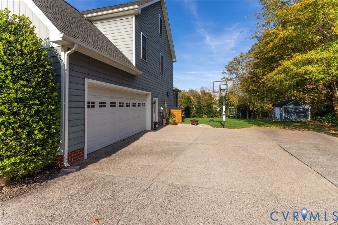 Horizontal lap siding exterior, attached multi-car garage, expansive concrete driveway, and detached storage structure