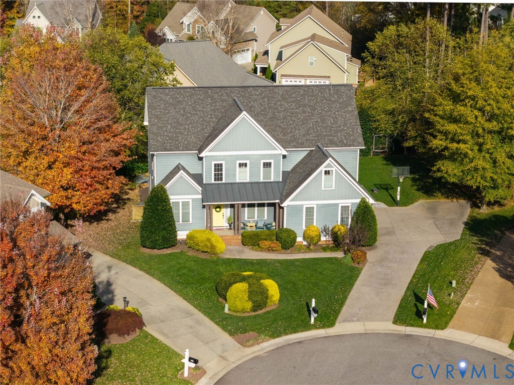 Two-story residence featuring lap siding, metal roof accents, a covered front porch, and an attached concrete driveway