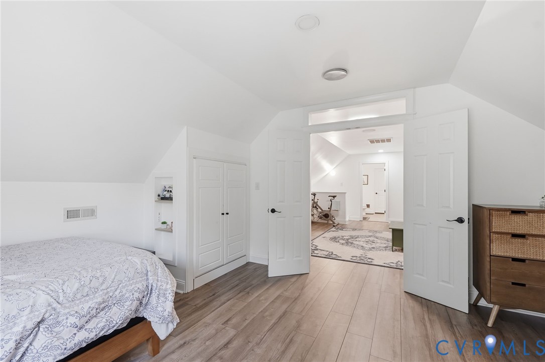 Wood-finish flooring, vaulted ceilings, integrated wall storage, and dual-panel interior doors with transom window detail