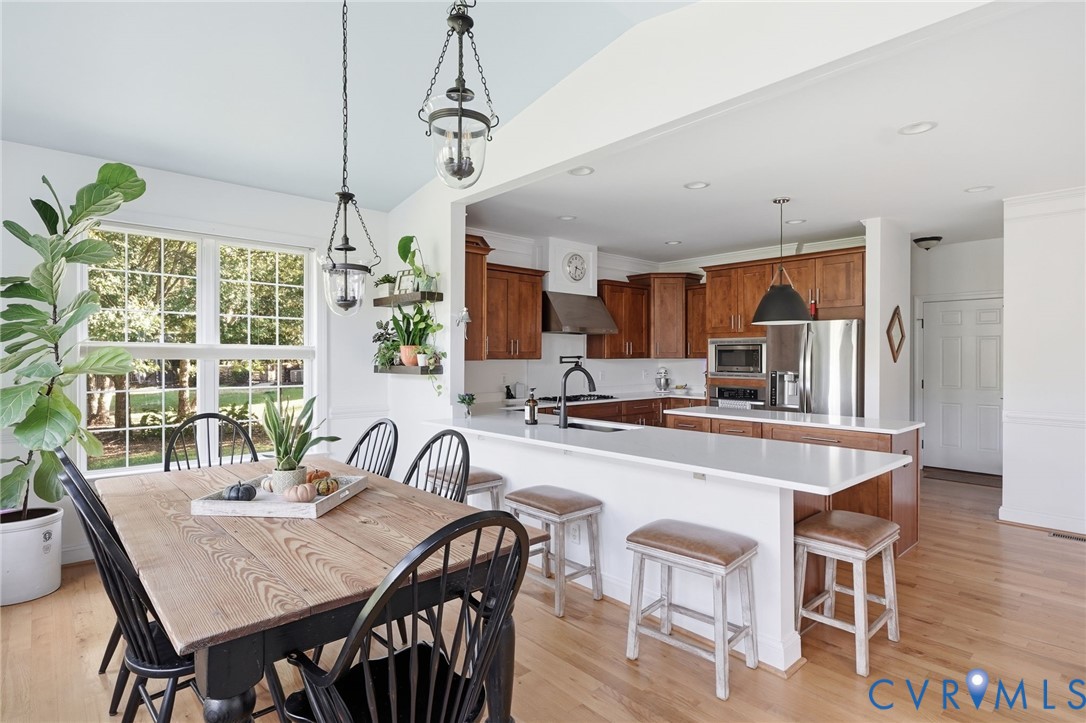 Kitchen featuring wood cabinetry, a central island with a solid-surface countertop, stainless steel appliances, recessed lighting, and wood-finish flooring