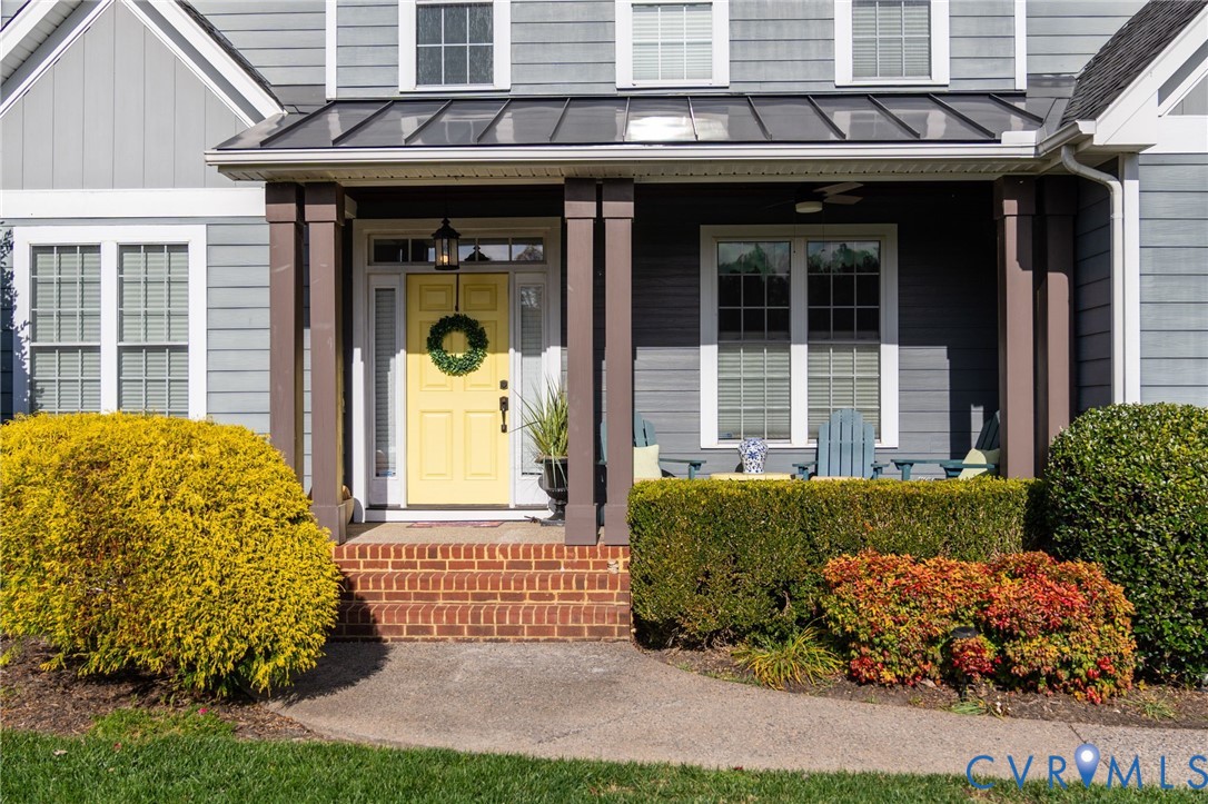 Covered front porch featuring a metal roof, brick steps, and square support pillars, accented by horizontal lap siding Covered front porch featuring a metal roof, brick steps, and square support pillars, accented by horizontal lap siding