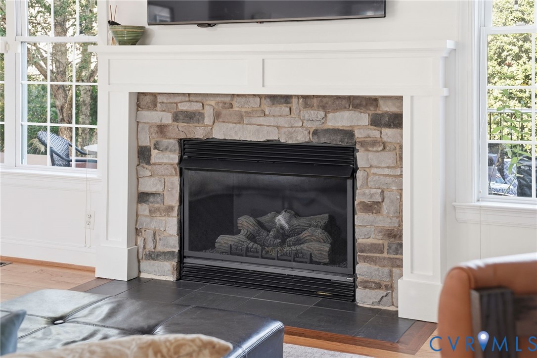Fireplace featuring a stone surround, white wood-finish mantel, and black tile hearth