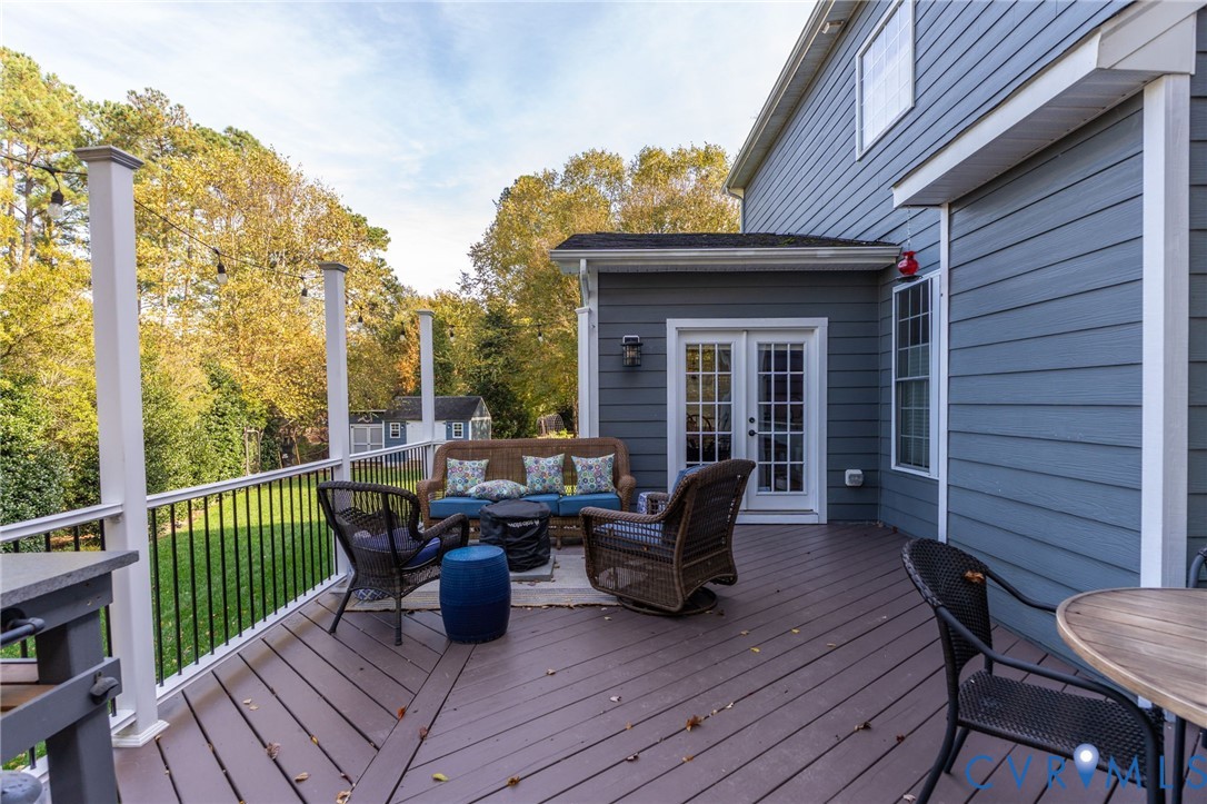 Rear deck featuring composite decking, vertical baluster railing, siding exterior, and French door access