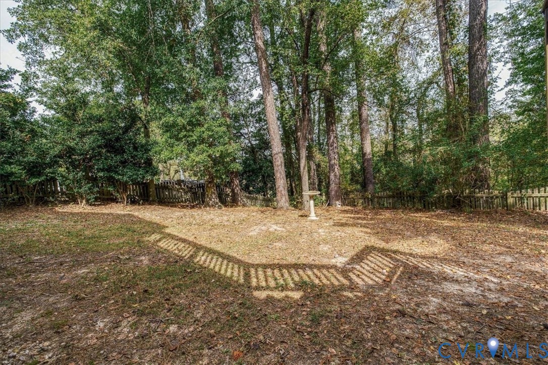 The large back yard has wood fencing.