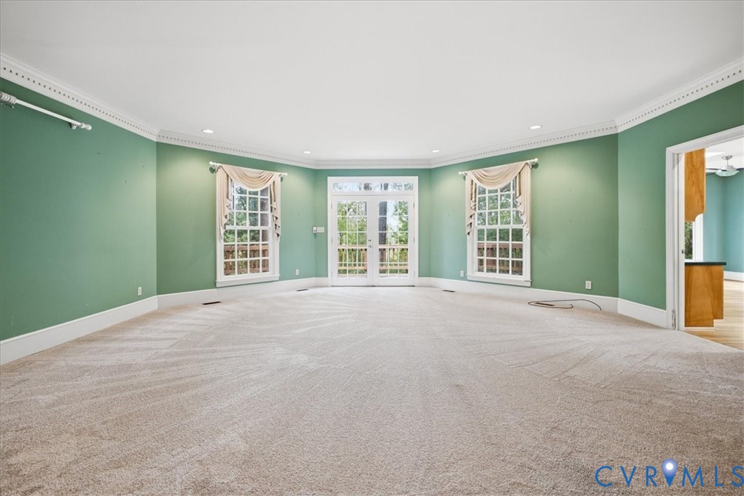 The Great Room is the true center of this lovely home.  Here you can see the French Doors leading to the deck which runs across the back of the home. Wide baseboards and Crown Molding.