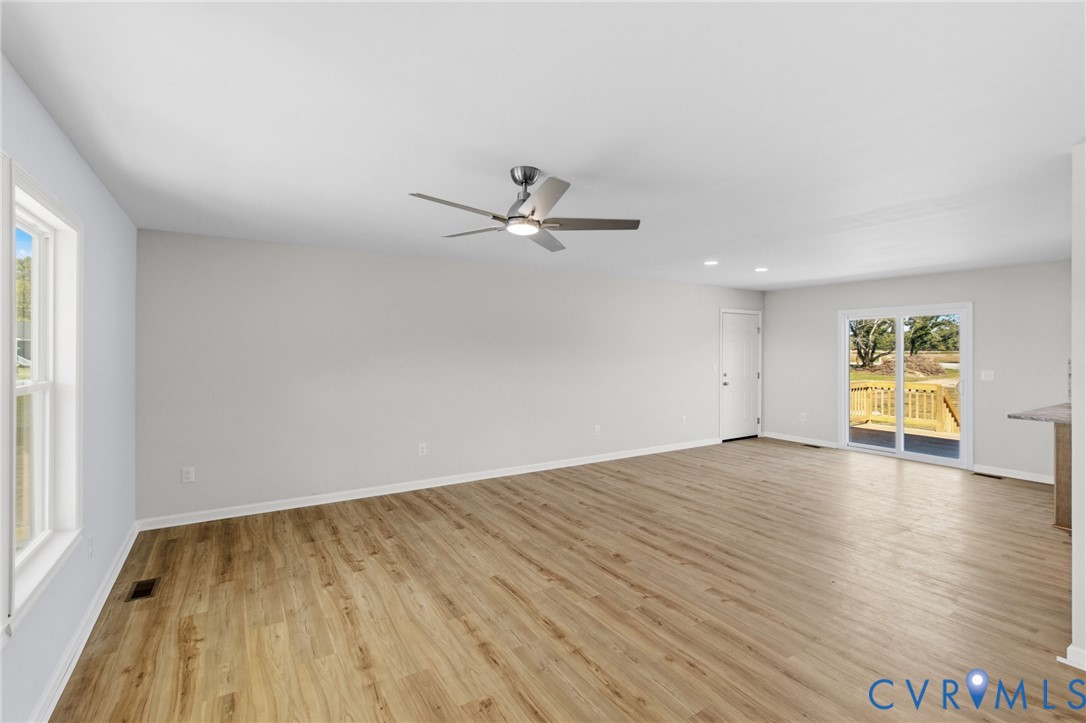 Neutral interior featuring wood-finish flooring, recessed lighting, a modern ceiling fan, and sliding glass doors with exterior access