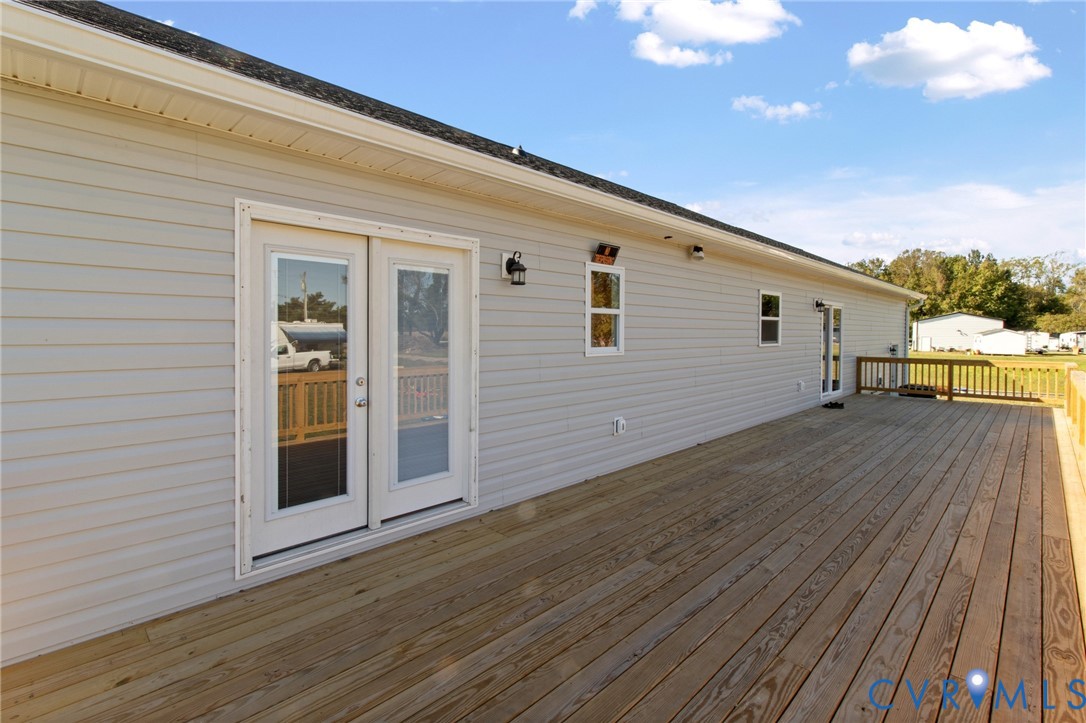 Expansive wooden deck featuring horizontal siding, glass-paned double doors, and wood-slat railings