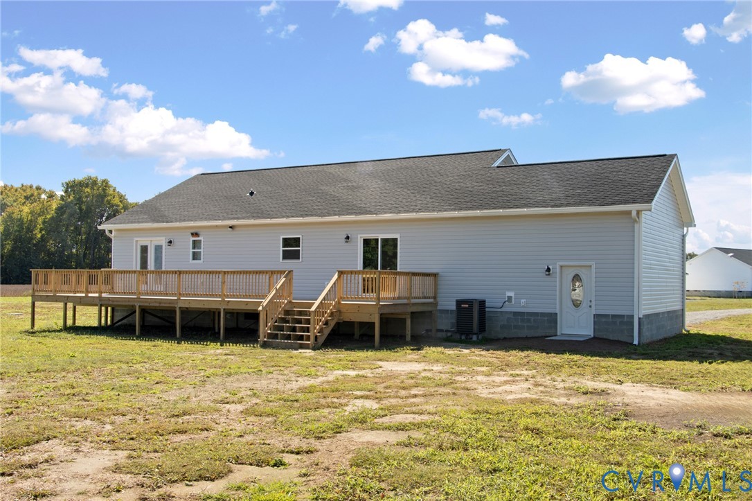 Exterior featuring light-gray horizontal siding, a composite shingle roof, a raised wood deck with balustrades, and a white entry door with an oval glass insert