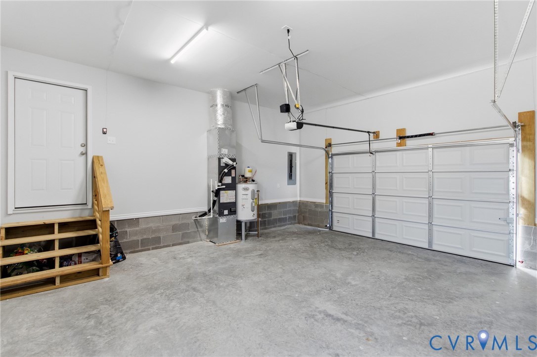 Garage interior featuring a concrete floor, sectional overhead door, built-in wooden staircase, and exposed HVAC system