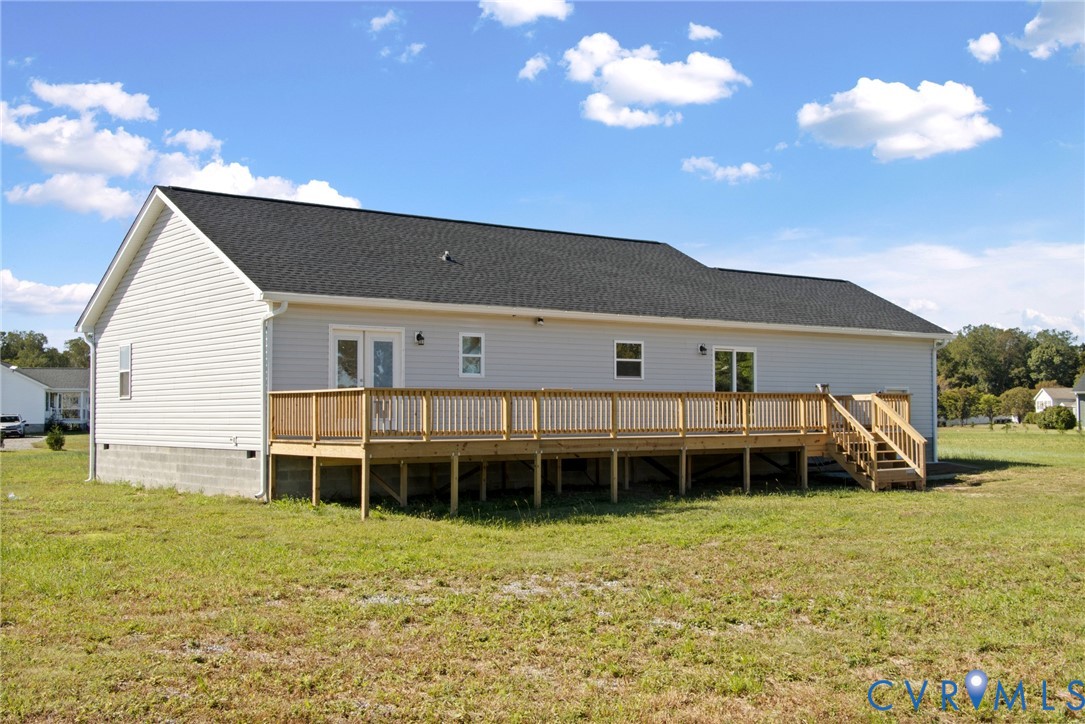 Exterior featuring light-colored horizontal siding, a gabled roof, a wood-framed deck with stairs, and multiple glass-panel doors